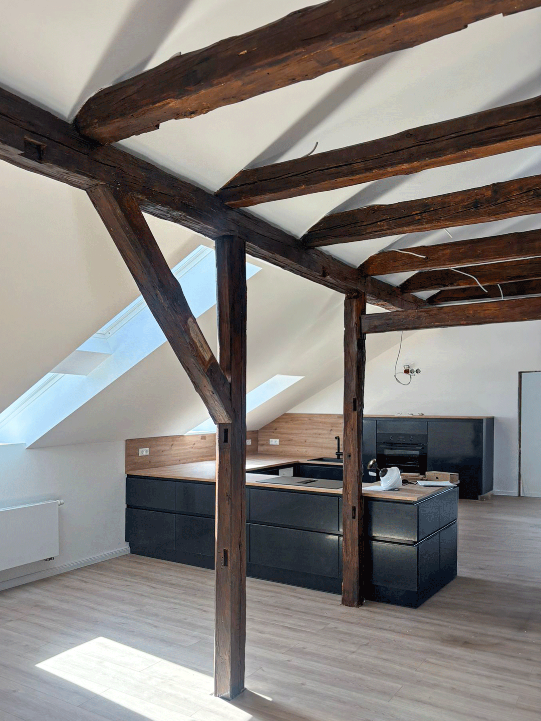 Freistehende Küche im Dachgeschoss Loft mit sanierten Holzbalken und Dachfenstern.