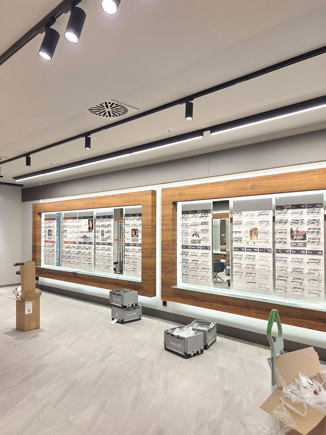 Produktwand im umgebauten Augenoptiker Laden mit beleuchteten Brillenwänden und moderner Verkaufsraumgestaltung.