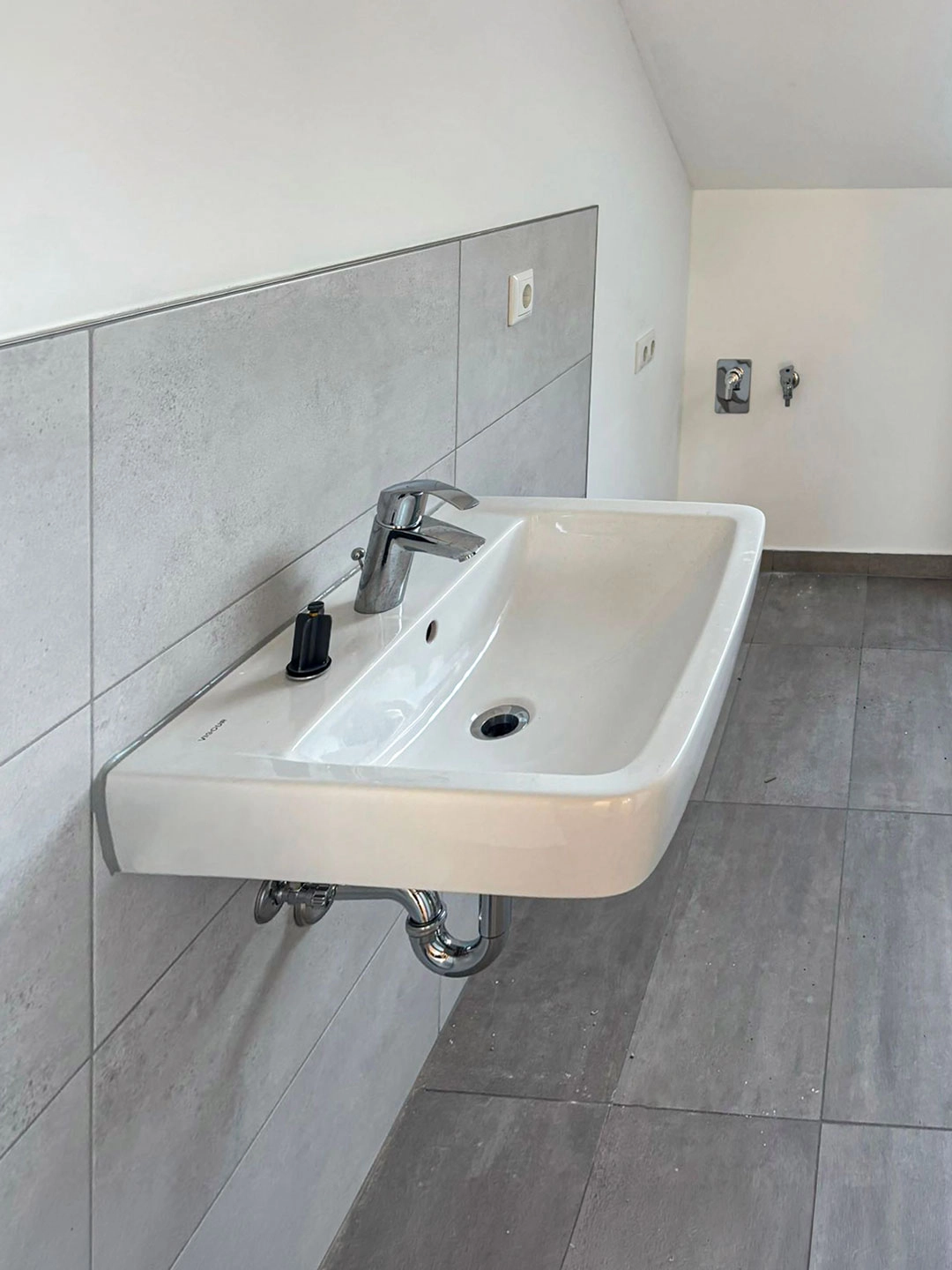 Modernes Waschbecken im sanierten Dachgeschossbad mit hellen Fliesen und zeitgemäßer Ausstattung.