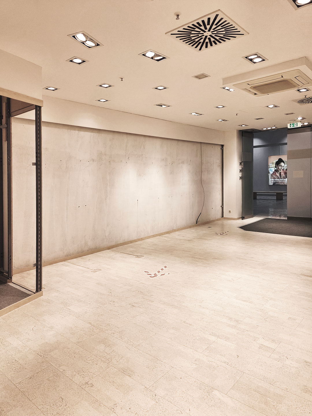 Leerer Verkaufsraum des Augenoptikers vor dem Ladenumbau mit freier Wandfläche und Bestandsbeleuchtung.