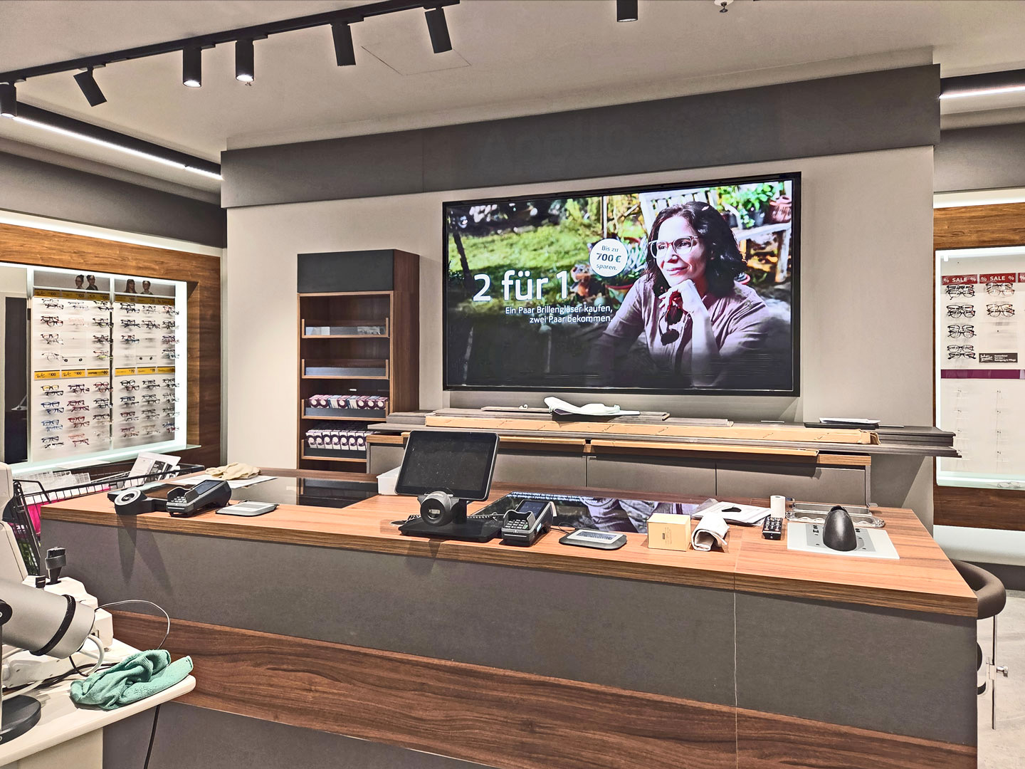 Kassenbereich nach Ladenumbau beim Augenoptiker mit moderner Theke, Bildschirm und Brillenwänden.